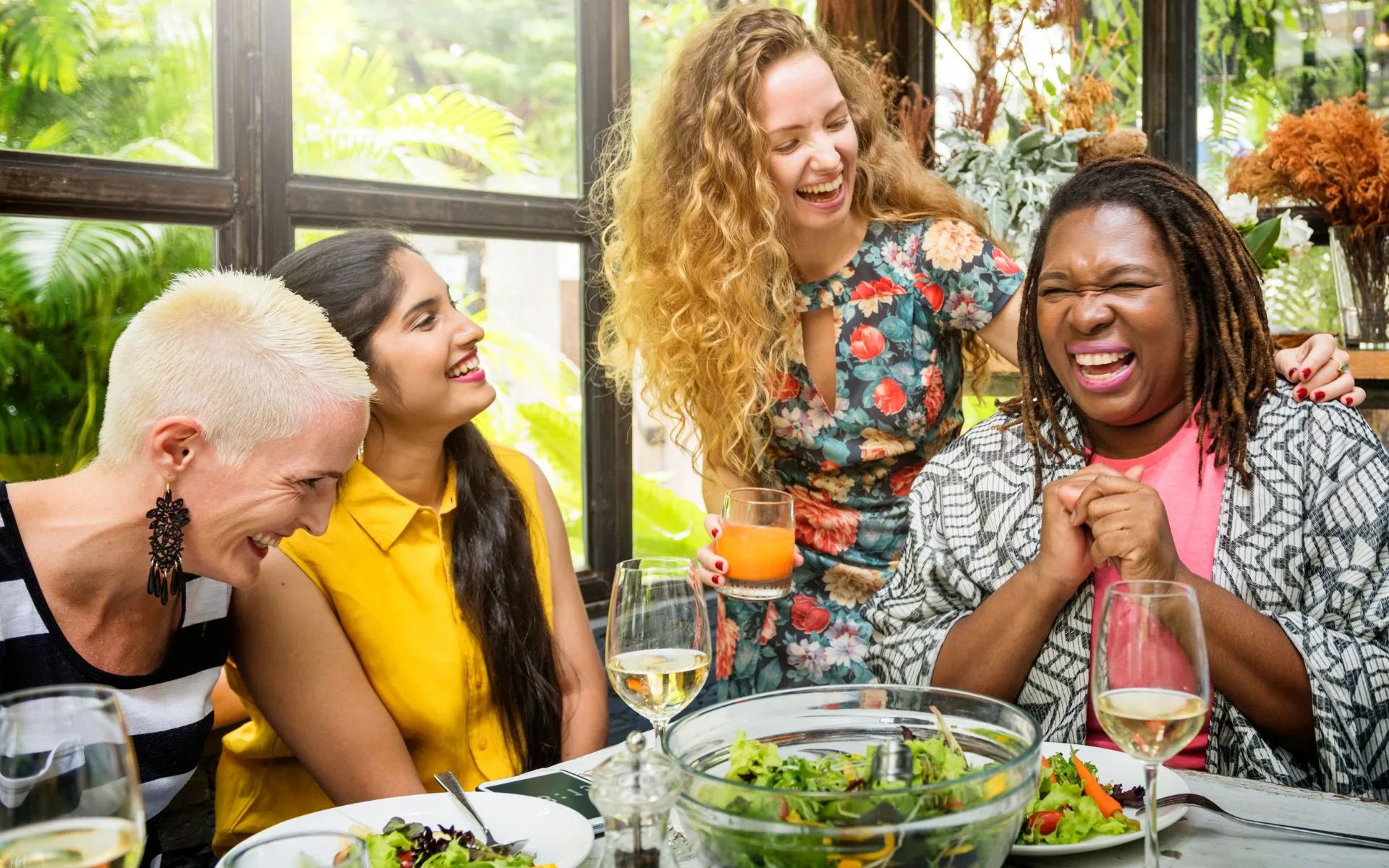 A group of women laughing together over a meal